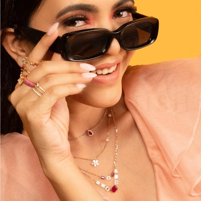 A beautiful young woman poses with trendy and chic rings and necklaces studded with diamonds and colorful gemstones from Khwaahish.