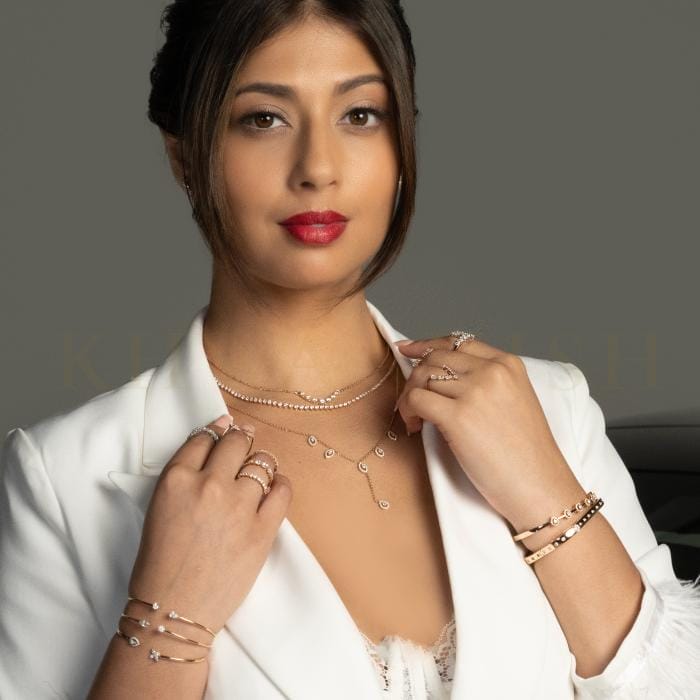 A stylish young woman wearing trendy diamond bracelets, necklaces, and rings.