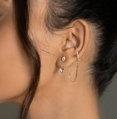 A young woman wearing trendy diamond earrings and diamond charms for her ears from the Gulz collection of Khwaahish.