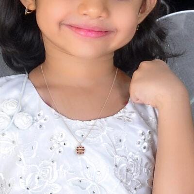 A small girl wearing Smiling Flora Diamond Kids Pendant in rose gold.